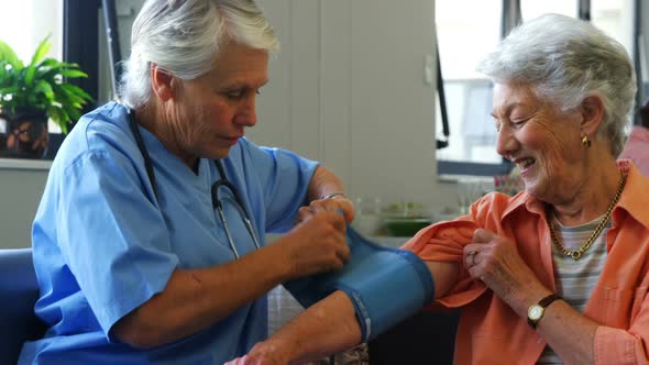 Female doctor checking blood pressure of senior woman 4k