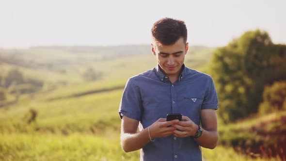 Young Man Uses Mobile Phone Outdoor