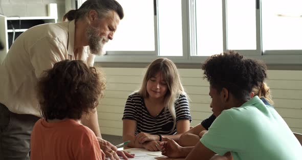 Male Teacher Teaching a Group of Multiethnic Students Working in a Group