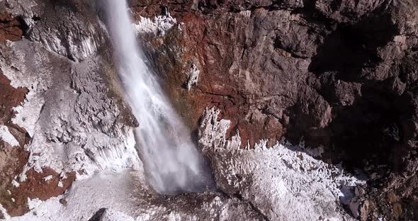 ice waterfall flow down heavily from a cliff on a snow covered ground in wild nature. snow like a sa