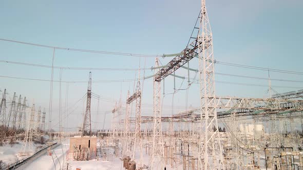 Aerial View of an Electrical Substation in Winter with High Pylons and Voltage Distribution Cables