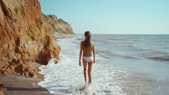 Back View Slow Motion Footage of Sexy Fitness Girl in Bikini Walking Along Sand Sea Beach with High