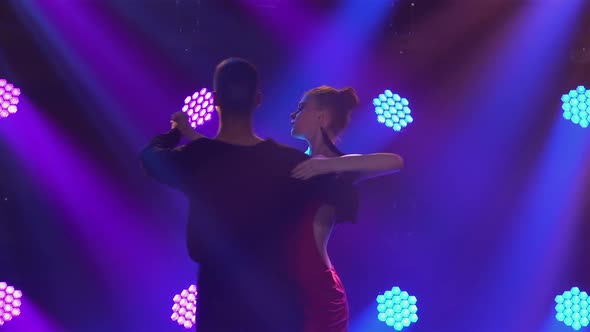Passionate Couple Dancing Elements of Argentine Tango in Dark Studio with Blue Lights