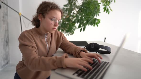 Closeup Shot of a Serious Teen Girl Thoughtfully Looking to a Laptop Screen and Typing