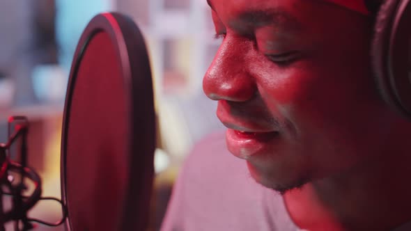 Close-Up of Afro-American Rapper Recording Song in Studio with Neon Light