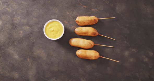 Video of corn dogs with dip on a black surface