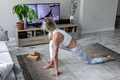 young woman doing online yoga exercise at home watching tutorial on tv screen - PhotoDune Item for Sale