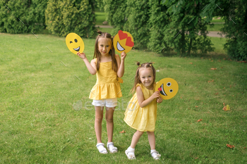a cardboard emoji in the hands of children