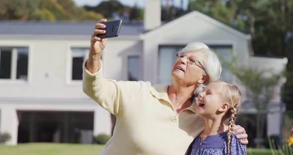 Grandmother and little girl making funny faces while taking selfie 