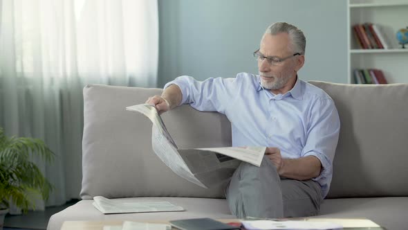 Senior Male Sitting on Couch and Reading Newspaper, Morning Ritual, Press