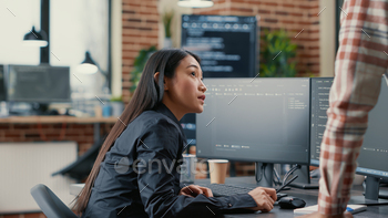 Database developer pointing pencil at computer screen with software compiling code