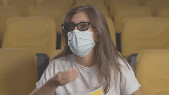 Engrossed Woman in Face Mask and 3d Glasses Eating Popcorn in Cinema. Absorbed Woman Watching Film