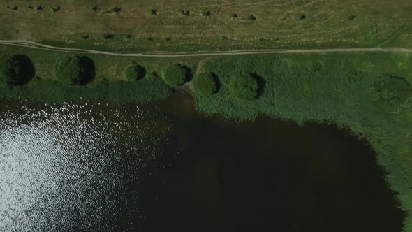 Flight Along The Shore Of The Lake. Sun Glare Is Visible On The Surface Of The Water