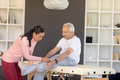Biracial female physiotherapist giving leg massage therapy to caucasian senior man at home - PhotoDune Item for Sale