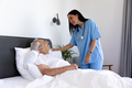 Biracial female health worker talking to caucasian senior man lying on the bed - PhotoDune Item for Sale