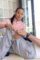 Biracial female physiotherapist giving leg massage therapy to caucasian senior man at home - PhotoDune Item for Sale