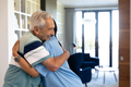 Caucasian senior man and biracial female health worker hugging each other at home - PhotoDune Item for Sale
