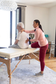 Biracial female physiotherapist giving back massage therapy to caucasian senior man at home - PhotoDune Item for Sale
