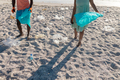 Low section of african american couple picking plastic waste on sand at beach - PhotoDune Item for Sale