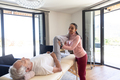Biracial female physiotherapist giving leg massage therapy to caucasian senior man at home - PhotoDune Item for Sale