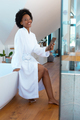 Portrait of smiling afro african american young woman with digital tablet in bathroom, copy space - PhotoDune Item for Sale