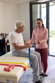 Biracial female physiotherapist helping senior man to exercise with resistance bands - PhotoDune Item for Sale