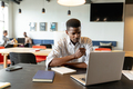 Serious young african american businessman working on laptop in creative office - PhotoDune Item for Sale
