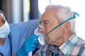 Biracial female health worker helping caucasian senior man to use oxygen mask at home - PhotoDune Item for Sale