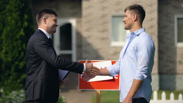 Real Estate Agent and New Apartment Owner Shaking Hands, Celebrating Good Deal