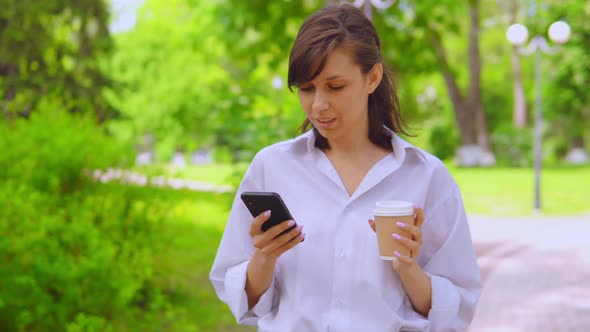 Young Businesswoman Chatting Online Drinking Coffee Stroll in Park