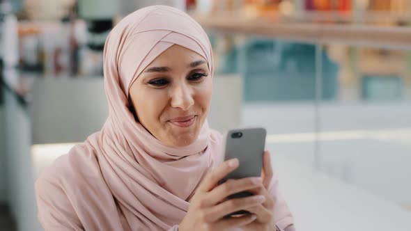 Happy Young Muslim Woman in Hijab Holding Smartphone Playing on Phone Islamic Girl Smiling Relaxes