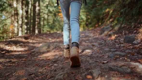 Slow Motion Woman Hiker Backpacker in Jeans and Vintage Yellow Hiking Boots Walks Along Rough Trail