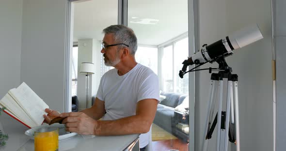 Man reading book while eating breakfast on table 4k