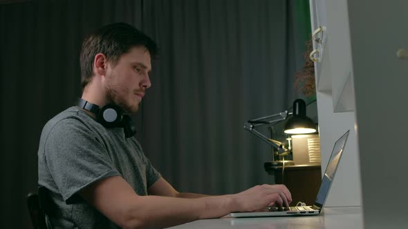 Man Listen Music on Headphones Use Laptop at Night