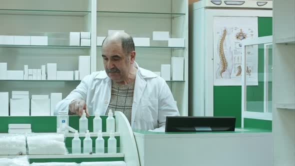 Senior Male Pharmacist with Mustache Posing at the Drugstore, Working with Medicine and Computer