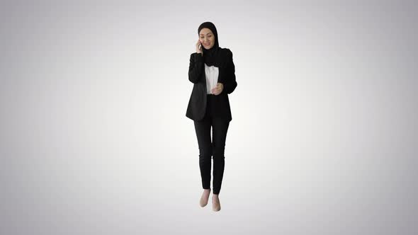 Attractive Modern Muslim Woman Walking and Talking on Cell Phone on Gradient Background