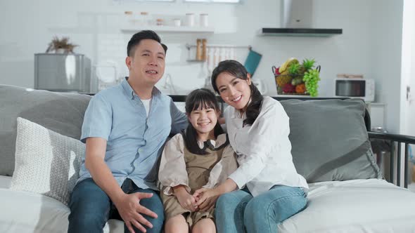 Portrait of Asian family Father mother and young kid looking at camera with smile together at home.