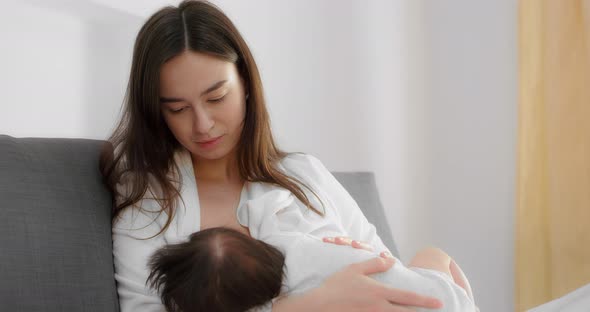 Mother is Breastfeeding Her Newborn Baby in the Nursery