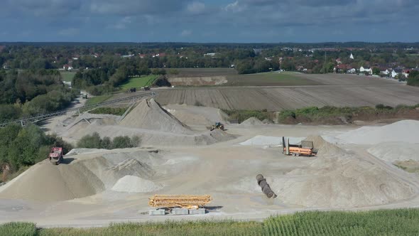 An excavator at work at a hugh sand pit in aerial view.