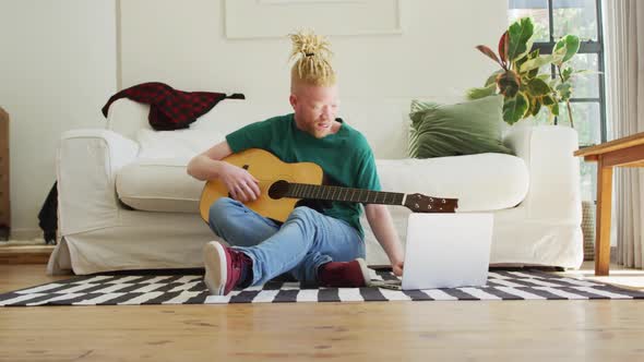 Albino african american man with dreadlocks playing guitars and singing