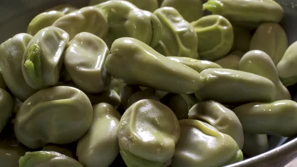 Close up of Fava beans spinning.  The beans have been boiled so the skin is wrinkled and loose and r