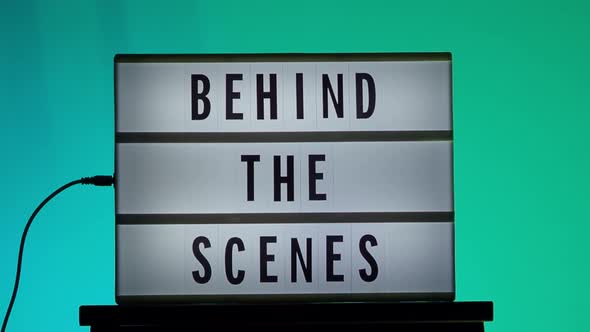 Behind the scene letters on cinema light box. Black text on white LED lightbox of word Behind the