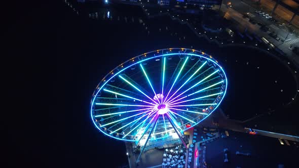 Helicopter View Passing Over Bright Ferris Wheel at Night