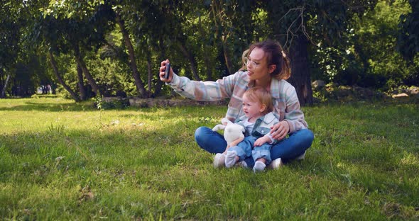 A Young Mother with a Child on a Walk During an Online Video Call  Mom Shows Her Daughter to Dad