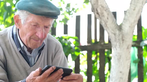 The Old Grandfather is Crying Looking at His Smartphone