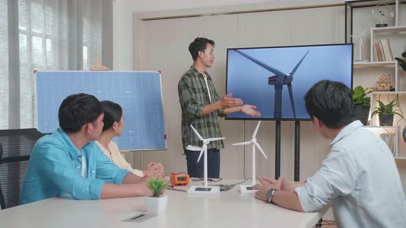 Asian Man Engineer With Solar Cell Presenting About The Wind Turbine At The Office