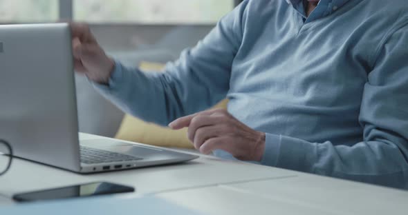 Senior man sitting at desk and using a laptop