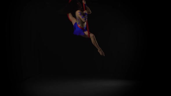 Female Aerial Gymnast Performing on a Red Silk in a Black Background. Exciting Acrobatic Show 058