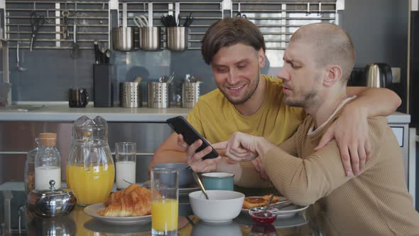 Gay Couple with Mobile Phone Chatting during Breakfast