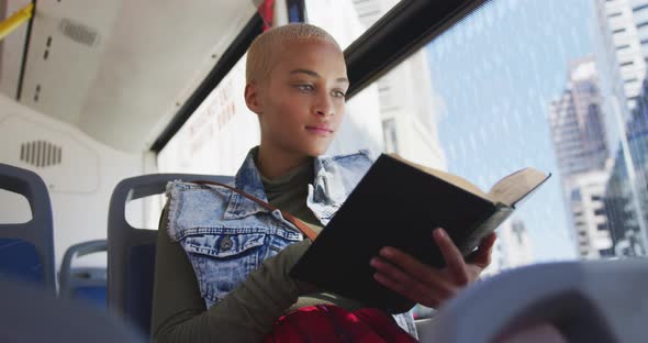 Mixed race woman taking the bus and reading a book